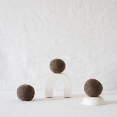 three wool balls sitting on top of a white stand next to each other in front of a white background