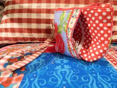 a red and white pillow sitting on top of a bed next to a blue comforter