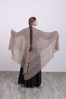 a woman wearing a brown shawl standing on top of a hard wood floor next to a white wall