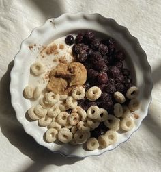 a bowl filled with cereal and fruit on top of a white cloth covered tablecloth