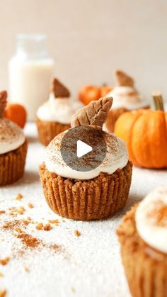 several cupcakes with frosting and decorations on them sitting next to some pumpkins