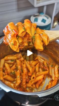 a ladle full of pasta being stirred by a wooden spoon in a pot on the stove