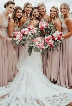 a group of women standing next to each other in dresses and holding bouquets together