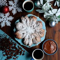 powdered sugar covered pastry on a blue plate next to two cups of coffee