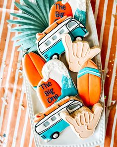 decorated cookies in the shape of campers on a plate with palm leaves and pineapples