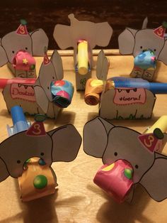 several elephant shaped toys are sitting on a table with markers and crayons in front of them