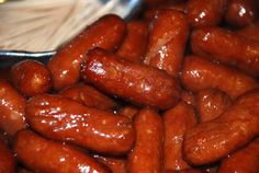 a pile of hot dogs sitting on top of a metal pan covered in ketchup