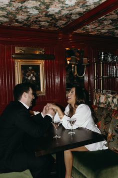 two people sitting at a table holding hands