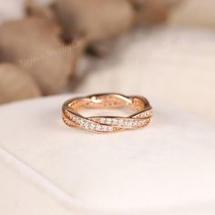 a gold wedding band with three rows of diamonds on the inside of it, sitting on top of a white cushion