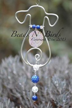 a blue and white beaded wind chime hanging from a metal stand on top of some bushes