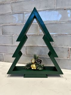 a wooden christmas tree with pine cones in the center on a white countertop next to a brick wall