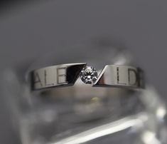 a close up view of a diamond ring on top of a clear glass block surface