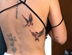 a woman's back with two birds and flowers on her left side ribcage