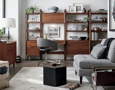 a living room filled with furniture next to a wall mounted book shelf and a window