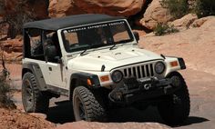 a white jeep driving down a rocky road