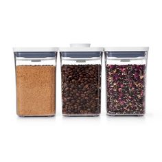 three glass containers filled with different types of beans and coffee beans on a white background