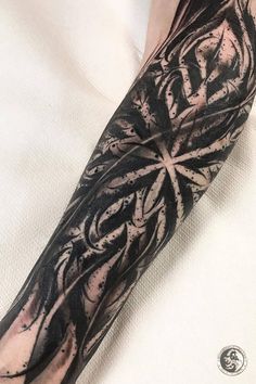 a man's arm covered in black ink with an intricate design on the sleeve