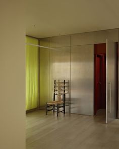 a chair sitting in front of a mirror on top of a wooden floor next to a red door