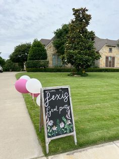 a chalkboard sign sitting on the side of a sidewalk in front of a house