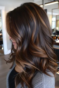 Woman with brown hair styled in loose curls, featuring caramel highlights. Fall Brown Highlights, Womens Highlights For Brown Hair, Chocolate Brown With Golden Highlights, Cute Hair Highlights For Brown Hair, Chocolate Brunette Hair With Highlights, Brown Sugar Highlights, Subtle Highlights For Dark Hair Curly, Black Hair With Honey Brown Highlights, Caramel Highlights On Brunette Hair