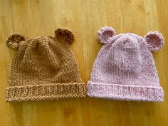 two knitted hats sitting on top of a wooden floor