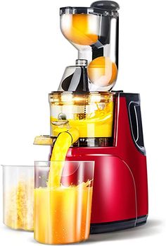 a red juicer filled with orange juice next to two glasses