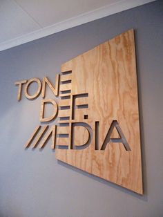 a wooden sign that reads tone deie media on the side of a gray wall