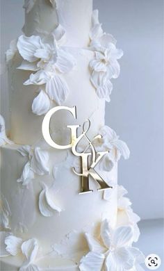 a wedding cake with white flowers and the initials g & k