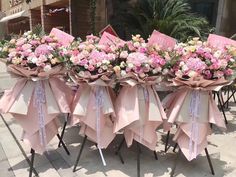 pink and white flowers are arranged on top of folding chairs with ribbons tied around them