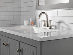 a bathroom sink sitting under a mirror next to a white tiled wall