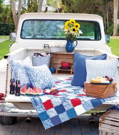 the back of a pickup truck with picnic food and drinks on it's bed