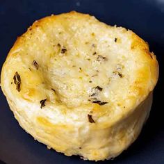 a piece of bread that is sitting on a black plate with some kind of food in it