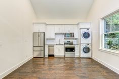 an empty kitchen with white cabinets and appliances