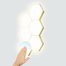 a hand reaching up towards a light that is on top of a wall with hexagonal shapes