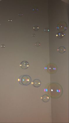 soap bubbles floating in the air on a white wall