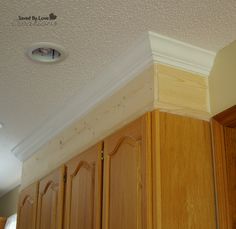 the corner of a kitchen with wooden cabinets and an overhead light fixture on the ceiling