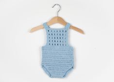 a blue knitted bodysuit hangs on a wooden hanger against a white background