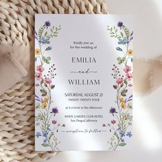 a wedding card with flowers and leaves on it next to a woven wicker basket