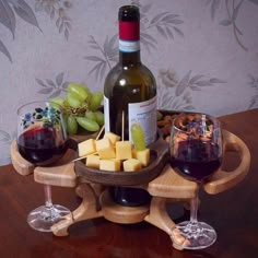 two glasses of wine, cheese and grapes on a wooden tray