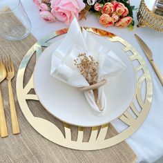 a place setting with napkins, flowers and gold cutlery on the tablecloth