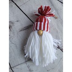 a red and white hat with tassels on top of a wooden floor next to a keychain