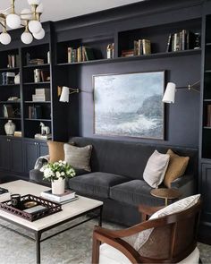 a living room filled with furniture and bookshelves next to a painting on the wall