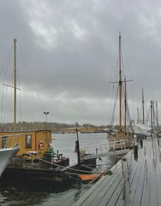 several boats docked at a dock on a cloudy day