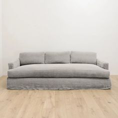 a couch sitting on top of a hard wood floor next to a white wall in an empty room