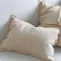 two pillows sitting on top of a white couch