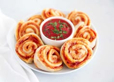 a white plate topped with pastries next to a bowl of sauce