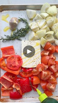 tomatoes, onions, and other vegetables are on a cutting board with a bottle of olive oil