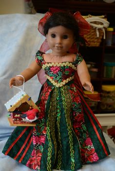 a doll dressed in a green and red dress is holding a piece of bread on a plate