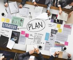 business people sitting around a table with plan written on it