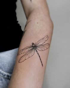 a woman's arm with a tattoo of a dragonfly sitting on top of it